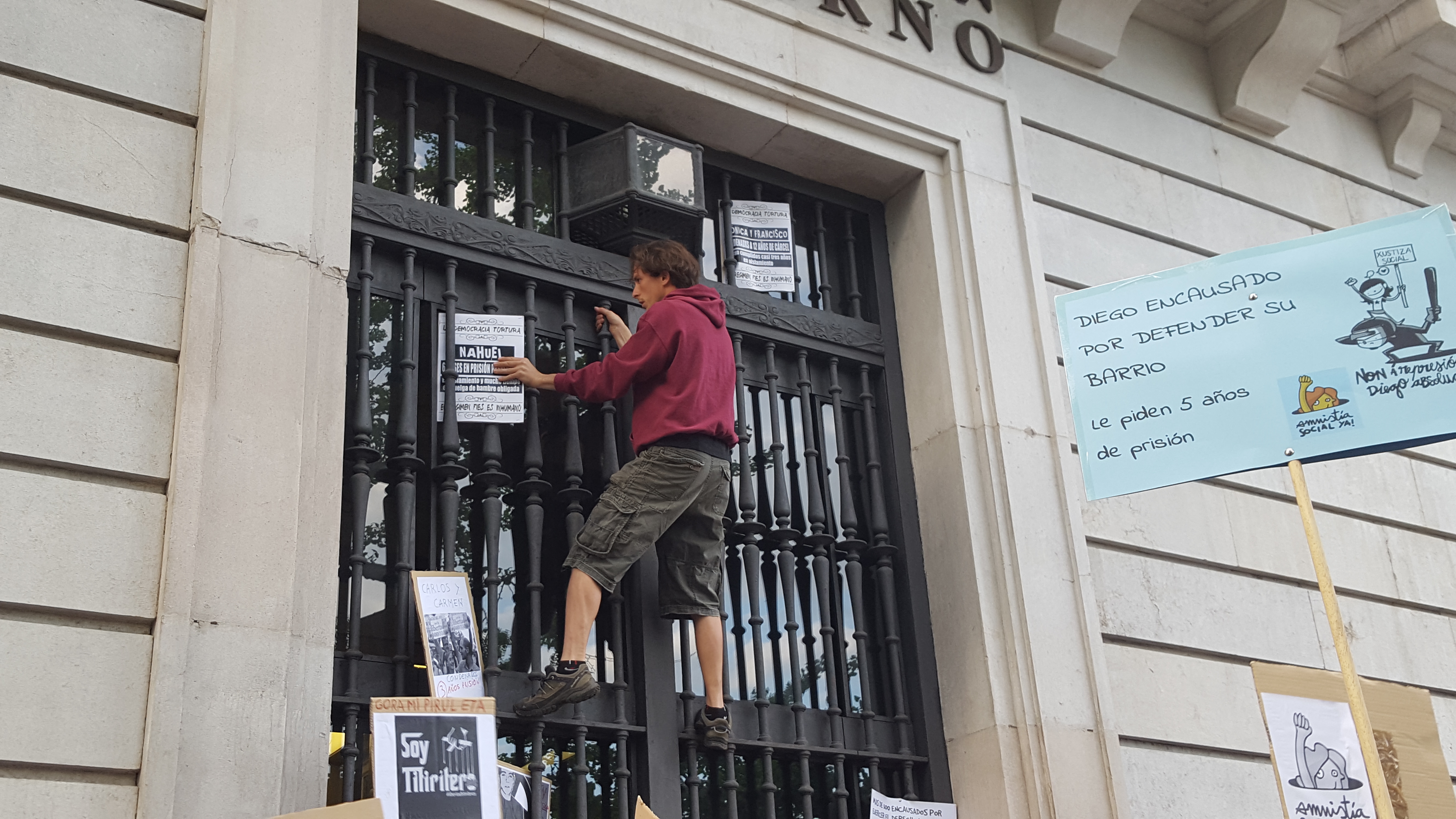 El joven identificado colocando pancartas en el edificio.