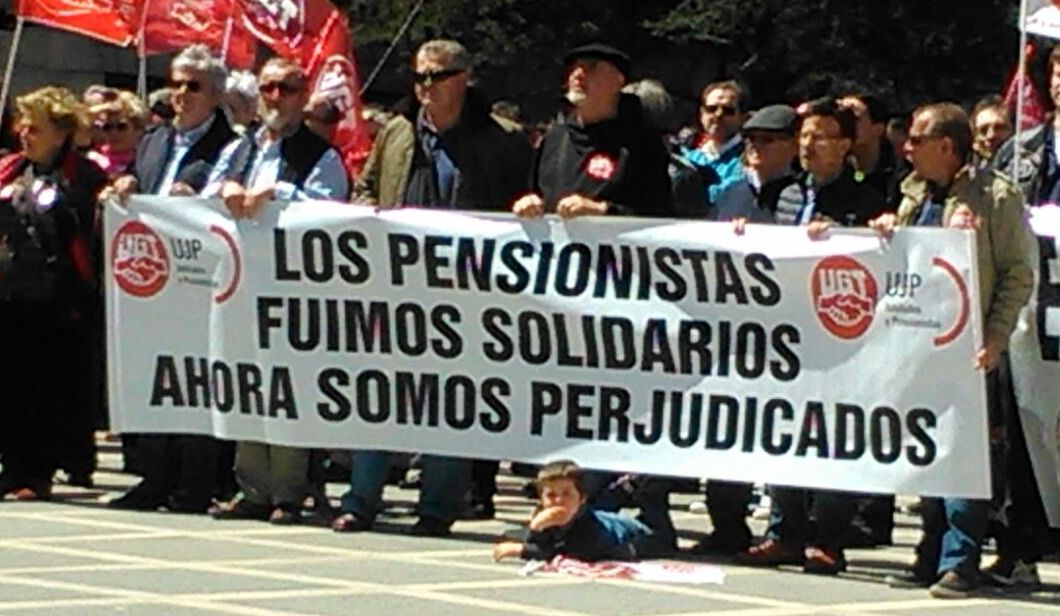 Un niño en el Primero de Mayo bajo la pancarta de los pensionistas
